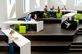 Das Bild zeigt Studierende in einer modernen Lernumgebung mit gro?en, hellen Fenstern.R?dern stehen.