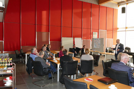 Projektleiter Prof. Franz stellt das Projekt KlimaLogis vor, die Teilnehmenden sitzen an verschiedenen Tischen und h?ren zu im Sitzungssaal des Rathauses in Bramsche 